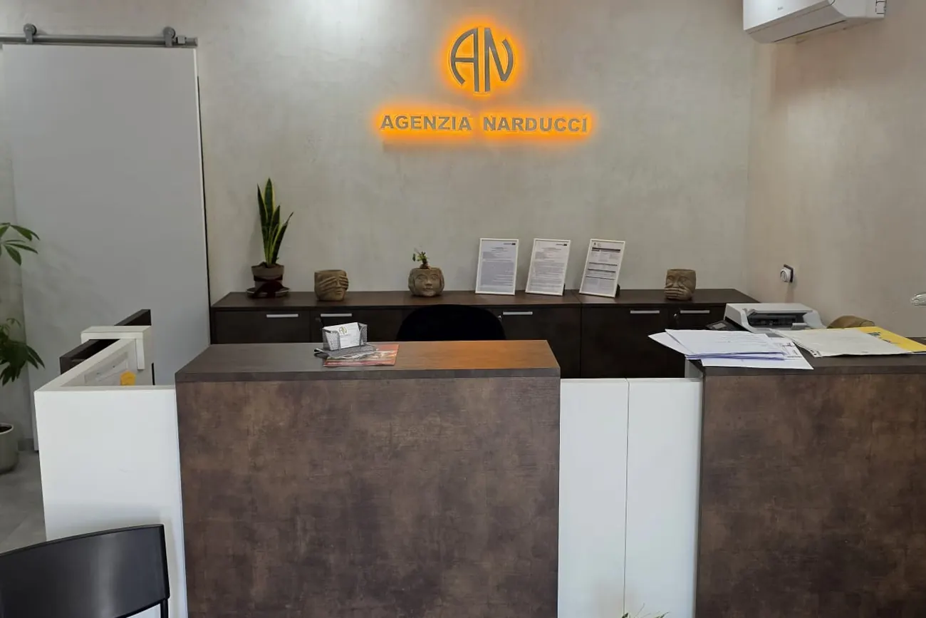 Il bancone della reception dell'Agenzia Narducci, col logo sulla parete